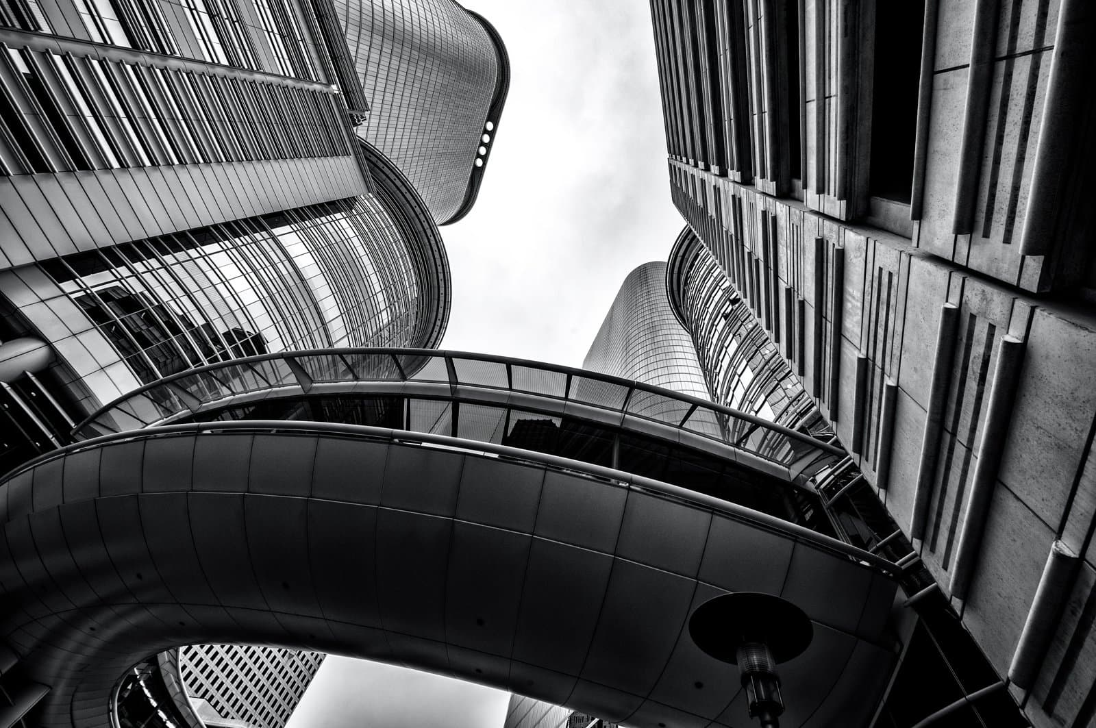 Modern skyscrapers connected by a curved pedestrian bridge
